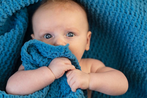 Un bambino carino che abbraccia una morbida coperta blu