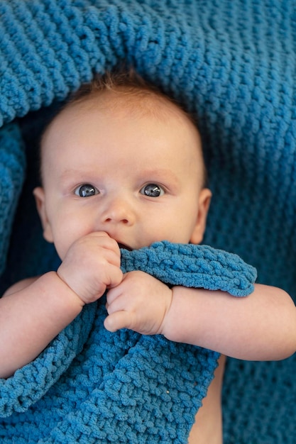 Un bambino carino che abbraccia una morbida coperta blu