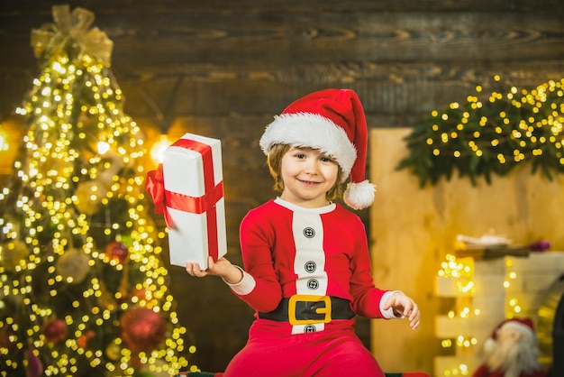 Un bambino carino e felice con un cappello da Babbo Natale con un regalo ha un regalo di Natale per un ragazzo di Natale