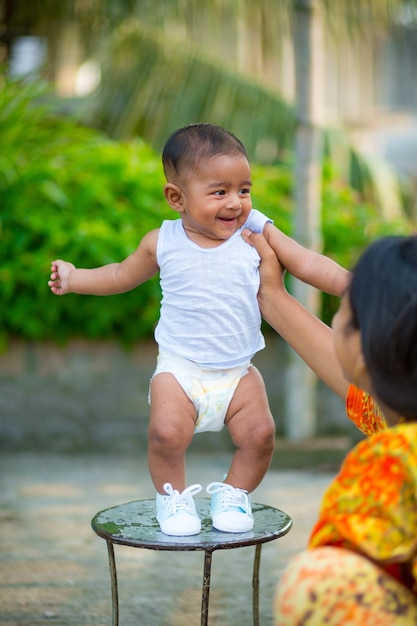 Un bambino carino è in piedi su una sedia d'acciaio e sorride a sua madre