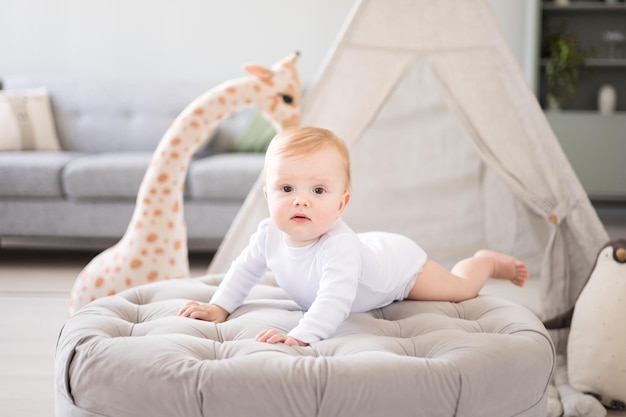 Un bambino carino e sano in una stanza per bambini spaziosa e luminosa a casa con un wigwam giocattoli morbidi tessuti per bambini Un bambino sta giocando nel soggiorno di casa