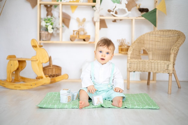 Un bambino carino e sano sta giocando con giocattoli educativi in legno in una luminosa e accogliente stanza per bambini a casa sullo sfondo di una casa di legno