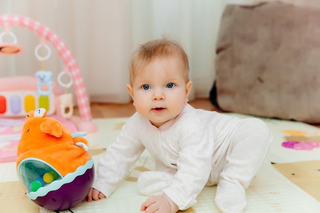 Un bambino carino è seduto su un tappeto tra giocattoli colorati un bambino sta giocando con un giocattolo