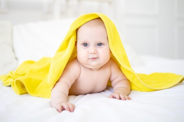 Un bambino carino felice sano è sdraiato a pancia in giù dopo aver fatto il bagno in un asciugamano e sorridente