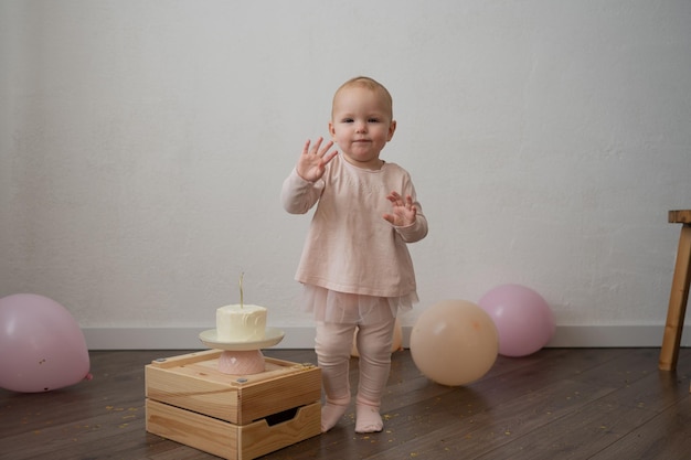 Un bambino carino festeggia il suo compleanno con una torta contro un muro bianco, una bambina in rosa è una