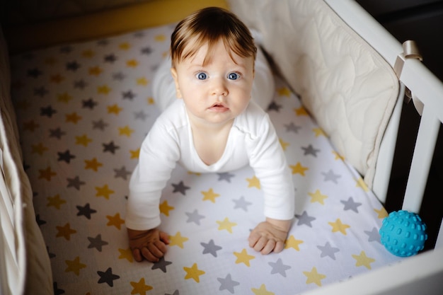 un bambino carino sorride mentre è seduto a letto