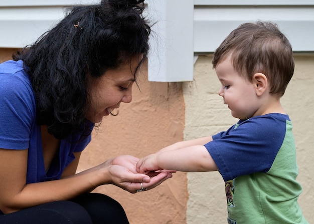 Un bambino carino sta giocando a ciottoli con la mamma sul portico sul retro.