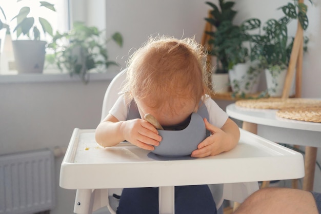 Un bambino che fa i suoi primi tentativi di mangiare da solo. Un bambino divertente che cerca di mangiare dalla ciotola di cibo.