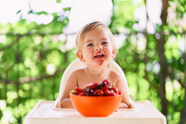 Un bambino che ride con la faccia sporca si siede al tavolo