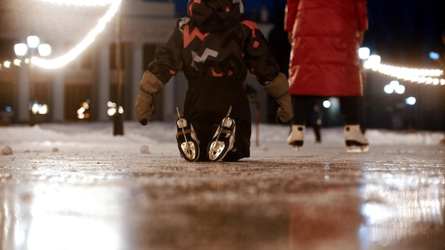 Un bambino che striscia in ginocchio sulla pista di pattinaggio pubblica