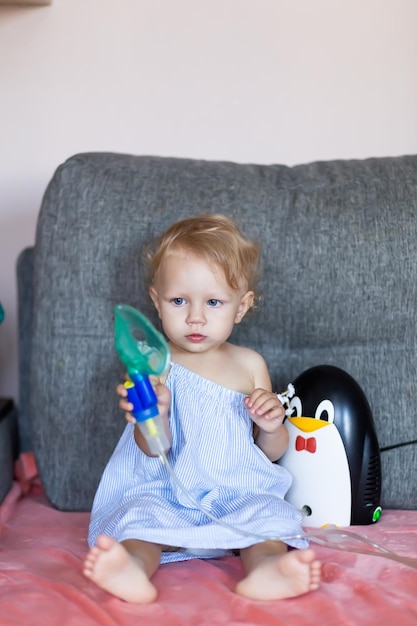 Un bambino con il moccio tiene in mano una maschera di un nebulizzatore