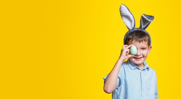 Un bambino con l'uovo di Pasqua su sfondo giallo