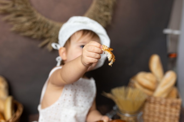 Un bambino con un cappello da chef tiene in mano un gambero.