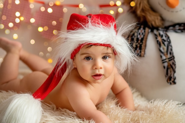 Un bambino con un cappello di Babbo Natale con un pupazzo di neve sullo sfondo di luci sfocate, il concetto di capodanno e Natale