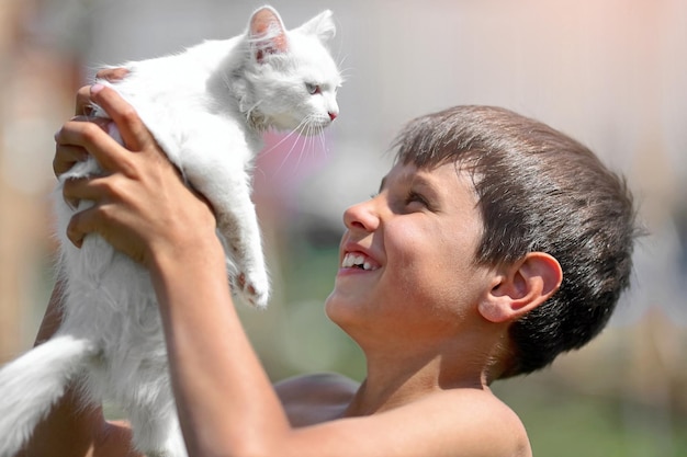 Un bambino con un gattino bianco Un ragazzo tiene in braccio un soffice animale domestico