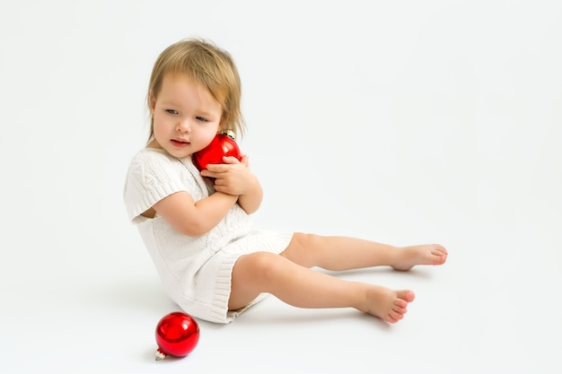 Un bambino con un maglione lavorato a maglia tiene in mano una palla di Natale abbracciandola