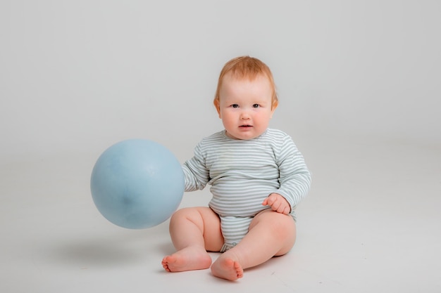 Un bambino con un vestito a righe tiene in mano un palloncino blu.