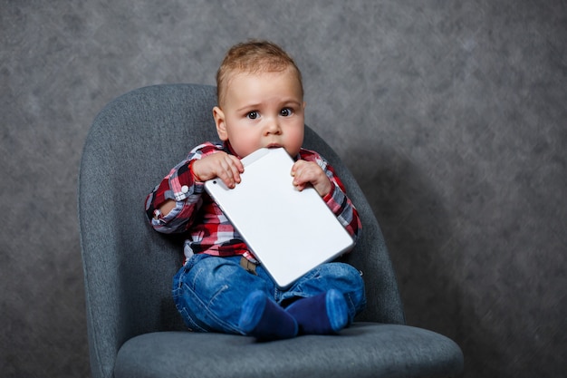 Un bambino con una maglietta rosicchia un tablet