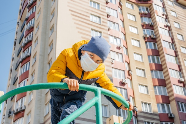 Un bambino con una maschera cammina nel parco giochi durante la quarantena. Resta a casa.