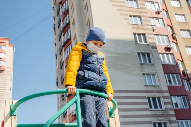 Un bambino con una maschera cammina nel parco giochi durante la quarantena. Resta a casa.