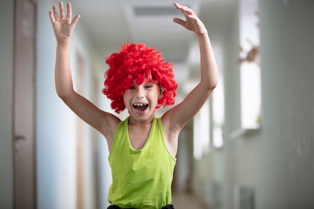 Un bambino con una parrucca brillante Ragazzo divertente con capelli artificiali rossi Scolaro artista