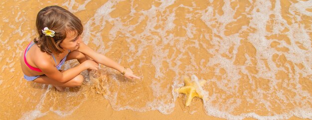 Un bambino con una stella marina in mano sulla spiaggia