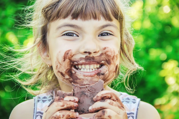 Un bambino dai dolci denti mangia cioccolato. Messa a fuoco selettiva