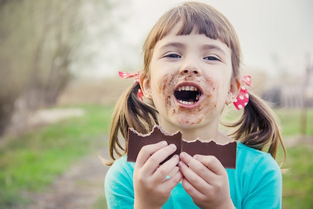 Un bambino dai dolci denti mangia cioccolato. Messa a fuoco selettiva