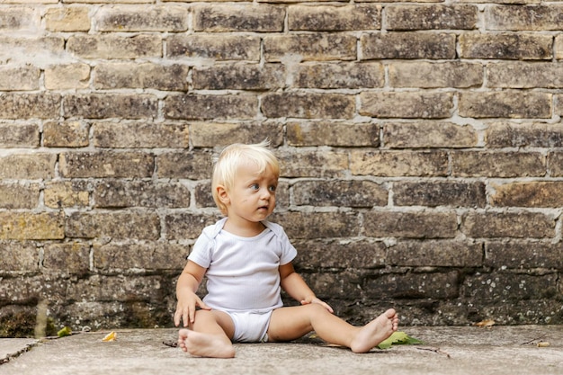 Un bambino davanti a un muro di mattoni rustico