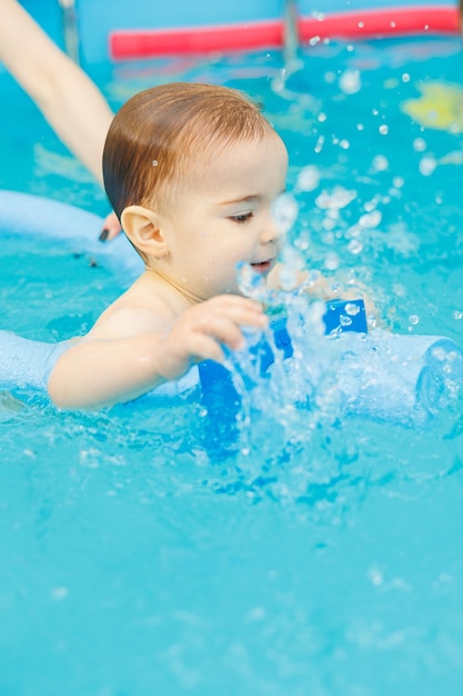 Un bambino di 2 anni impara a nuotare in piscina con un allenatore Lezioni di nuoto per bambini