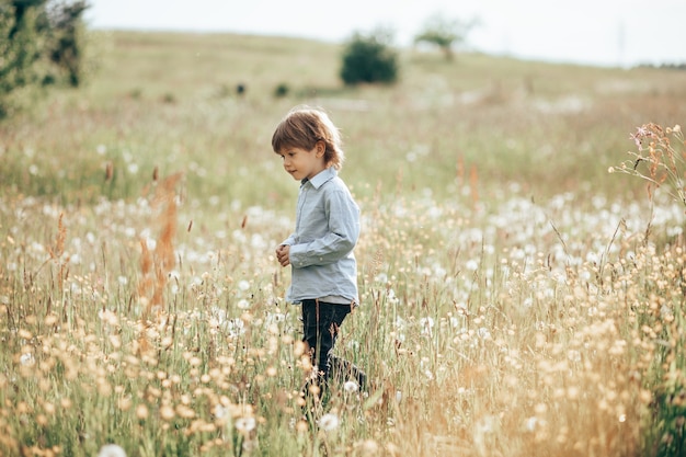 Un bambino di 3-4 anni cammina in un prato ridendo e divertendosi.