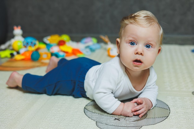 Un bambino di 5 mesi sorride e giace su un tappetino per lo sviluppo dello sviluppo del bambino