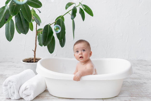 Un bambino di 8 mesi fa il bagno in una vasca da bagno con schiuma e bolle di sapone