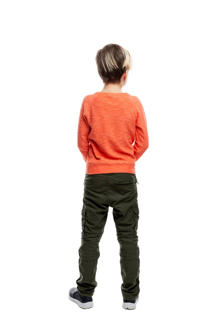 Un bambino di 9 anni indossa jeans e un maglione arancione