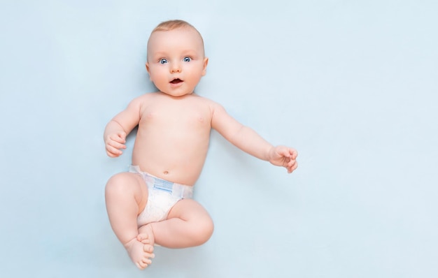 Un bambino di cinque mesi giace sulla schiena e guarda la telecamera con interesse