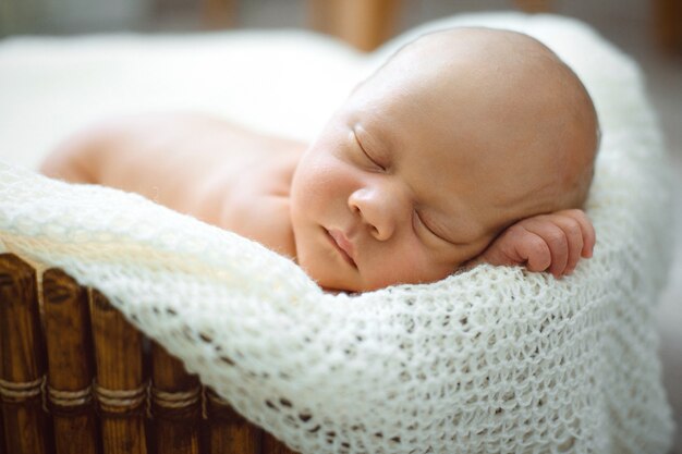 Un bambino di due settimane dorme in un cesto su una coperta di lana