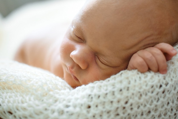 Un bambino di due settimane dorme in un cesto su una coperta di lana