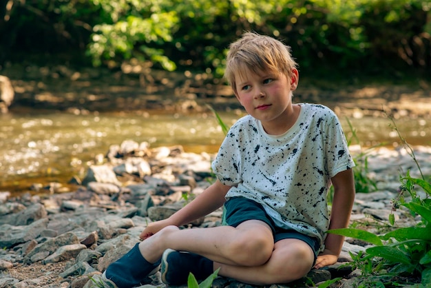 Un bambino di nove anni vicino a un piccolo fiume in estate