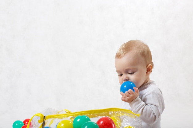 Un bambino di otto mesi sta facendo alcune attività su uno sfondo grigio.