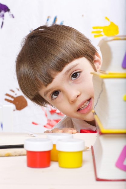 Un bambino di sette anni sta guardando fuori da una pila di dizionari. Avvicinamento