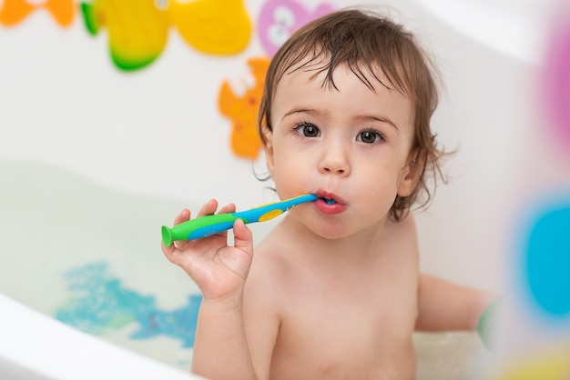 Un bambino di un anno si lava nella vasca da bagno gioca con i giocattoli impara a lavarsi i denti