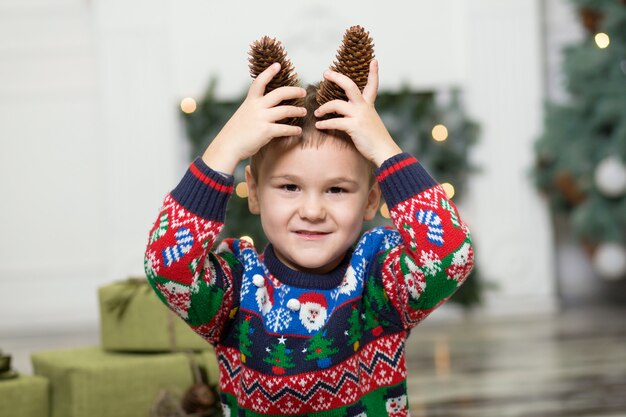 Un bambino di un ragazzo bambino che gioca sul pavimento con i coni per decorare l'albero di Natale.