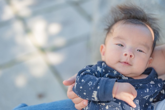 Un bambino è tenuto da una donna con un maglione blu.