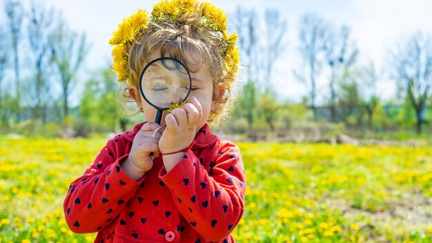 Un bambino esamina le piante con una lente d'ingrandimento Fuoco selettivo