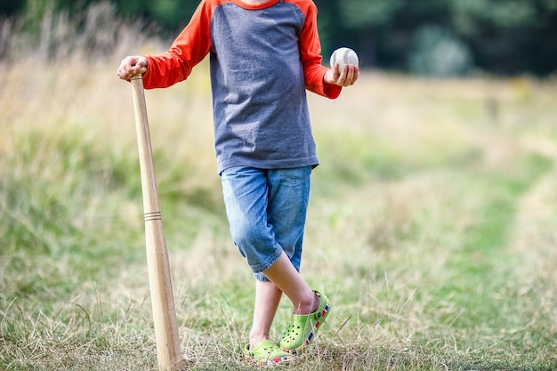 Un bambino felice con la mazza da baseball sul concetto di natura nel parco