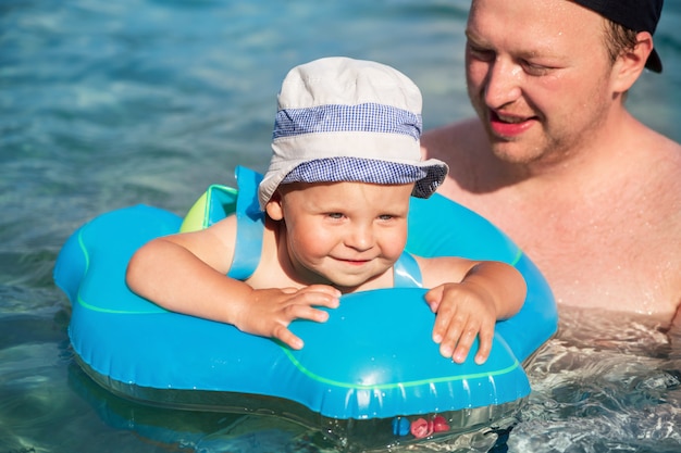 Un bambino felice con suo padre nuota in un anello di nuoto nel mare Adriatico