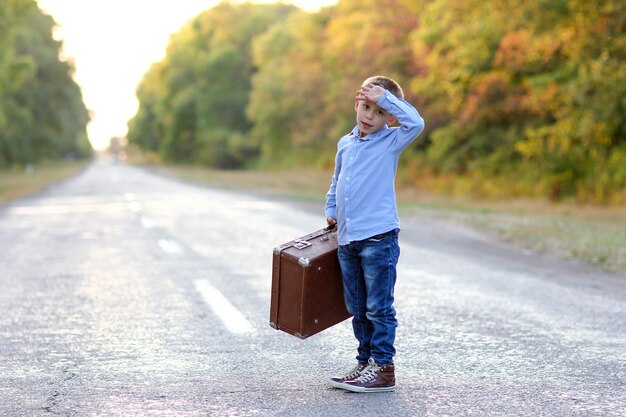 Un bambino felice con una valigia sulla strada nel viaggio del parco