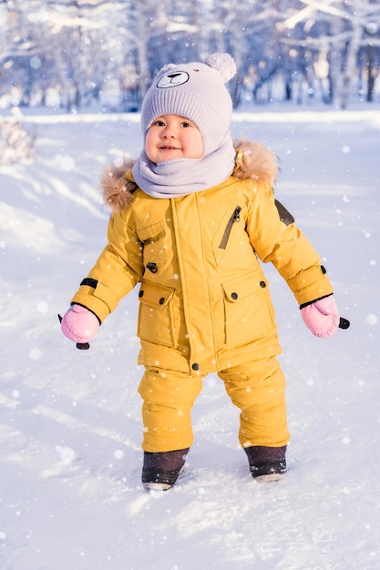 Un bambino felice in abiti invernali si gode la neve mentre cammina nel parco invernale Primo piano