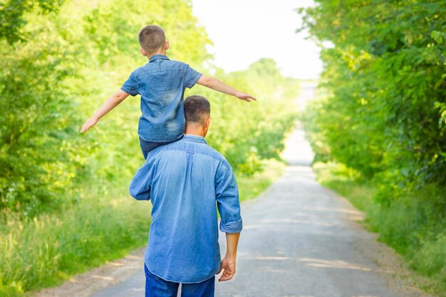 Un bambino felice sulle spalle di un genitore in natura durante il viaggio