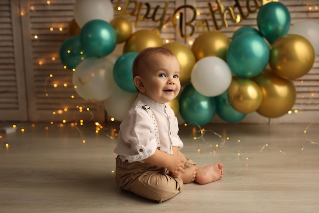 Un bambino felice sullo sfondo di palloncini con ghirlande festeggia il suo compleanno
